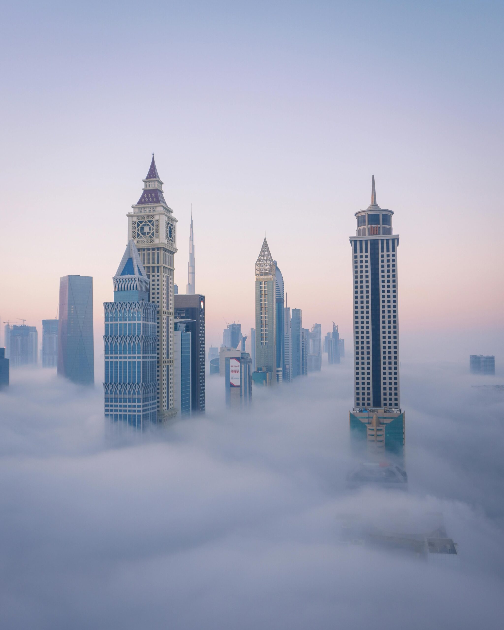 A breathtaking aerial view of Dubai's iconic skyline emerging through the clouds at sunrise.